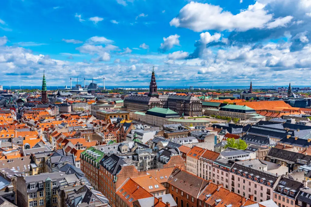 Aerial view of Copenhagen showing detailed cityscape with Christiansborg Palace and colorful rooftops under a blue sky, Denmark