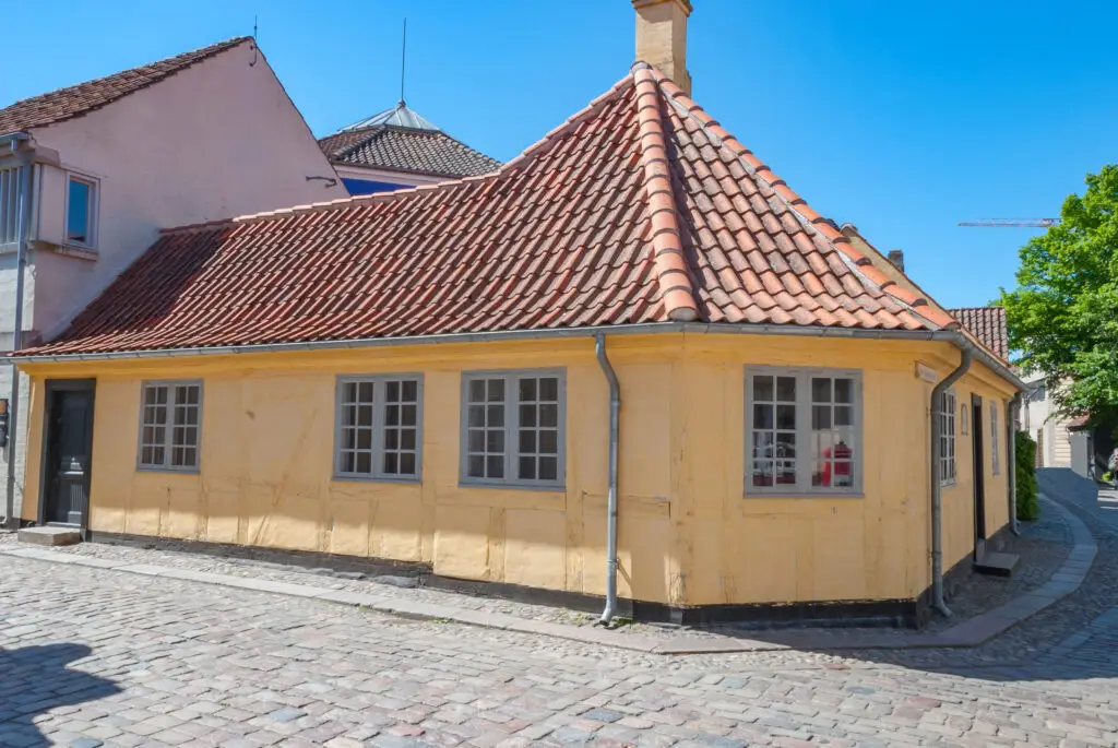 Traditional yellow building at HC Andersen Museum in Odense, Denmark, showcasing classic Danish architecture with a tiled red roof and cobbled street.