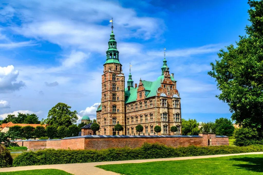 Panoramic view of the historic Rosenborg Castle surrounded by lush greenery in King's Garden, Copenhagen, Denmark, showcasing Scandinavian heritage and architecture.