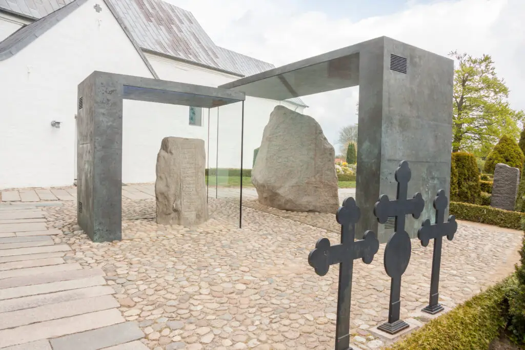 Historic Jelling church with ancient rune stones under protection in Denmark, showcasing early medieval Scandinavian heritage.
