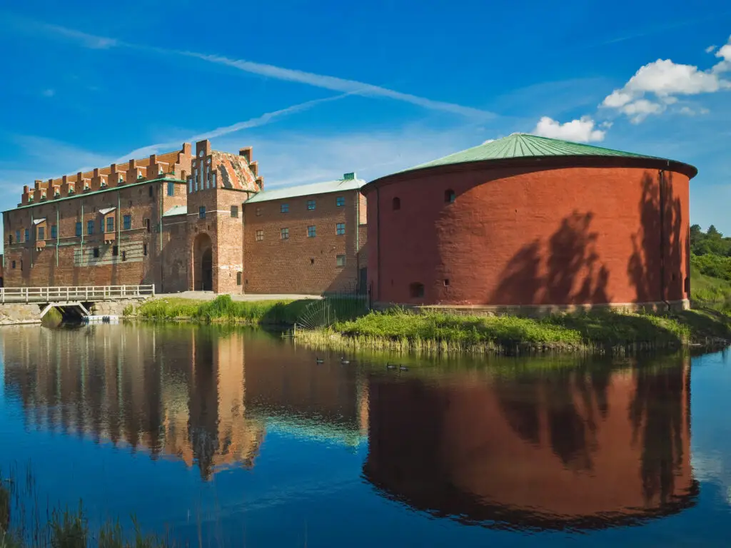 Scenic view of Schloss Malmöhus reflecting in water under a blue sky, Malmö, Sweden