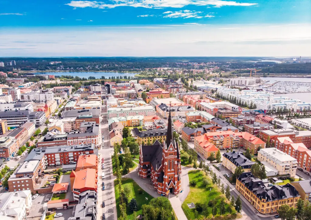 Aerial view of Lulea, Sweden, showing the cityscape with the prominent red Cathedral on a sunny day with clear blue sky.