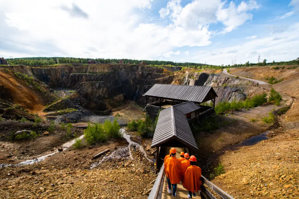 Visitors exploring the historic Falun Copper Mine in Sweden, a UNESCO World Heritage site, featuring a view of the expansive mining pit and surrounding natural landscape.