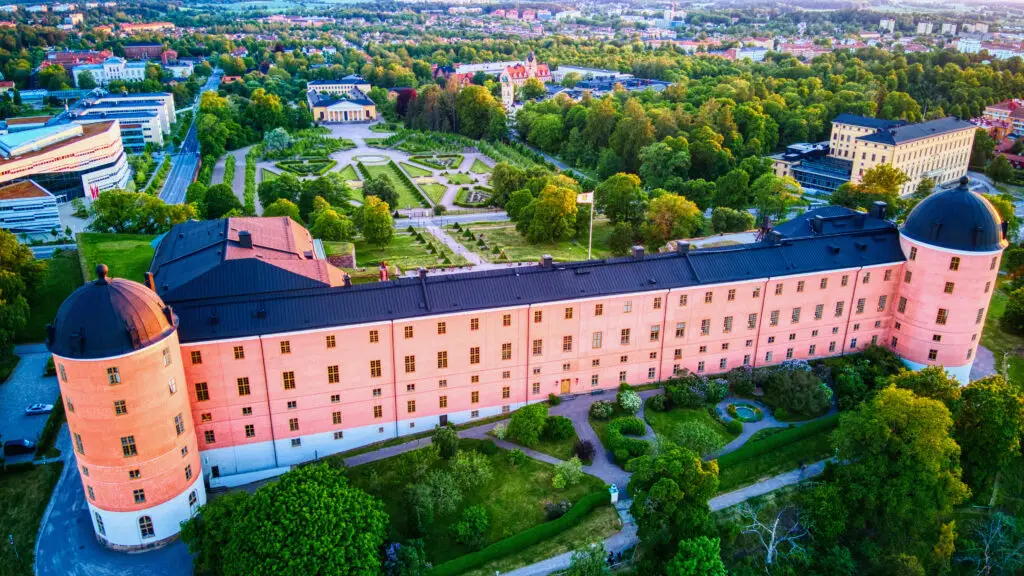 Aerial view of Uppsala Castle and Linneanum botanical garden in Sweden during sunset, showcasing historical architecture and lush greenery.