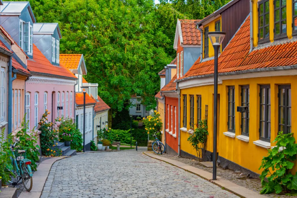 Colorful medieval street in the old town of Odense, Denmark, showcasing traditional Scandinavian architecture and cobblestone pathway.