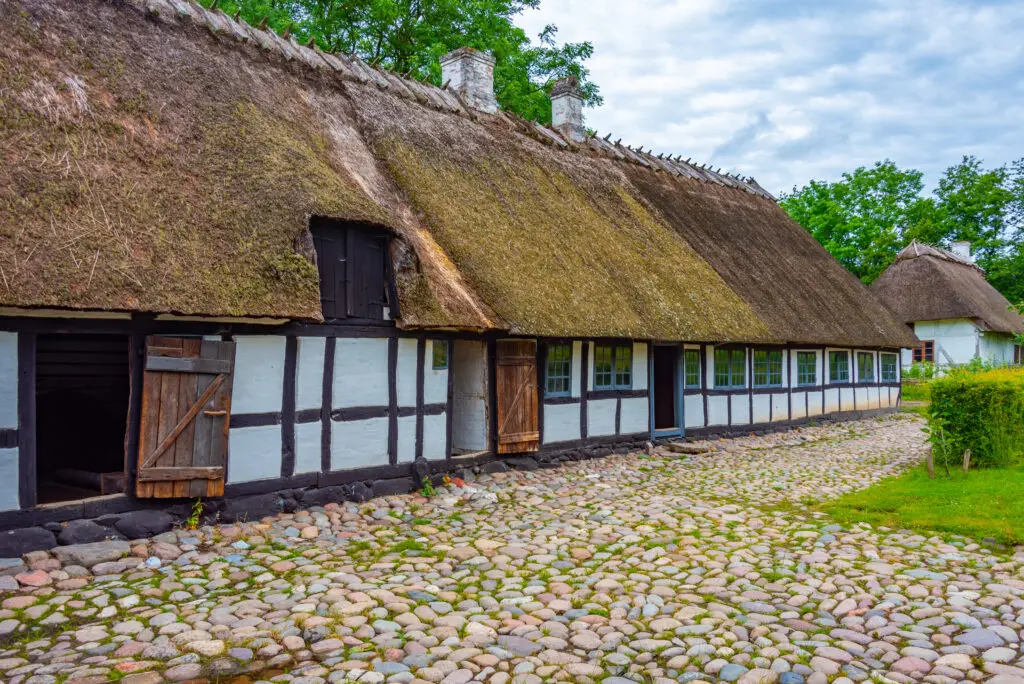 Traditional Danish thatched-roof houses at Den Fynske Landsby open-air museum in Odense, showcasing historic architecture in Denmark.