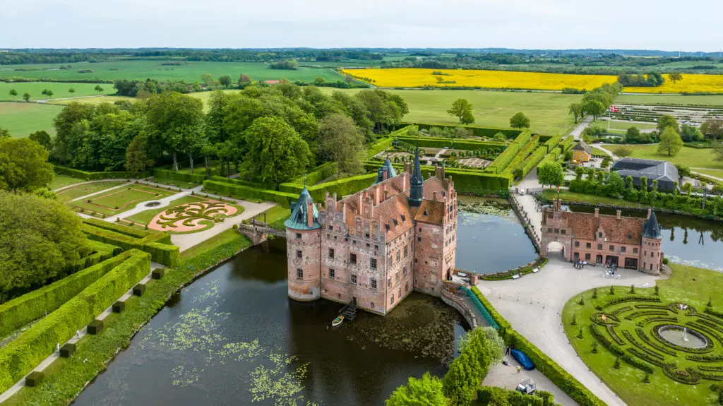 Aerial view of Egeskov Castle and Renaissance Garden in Kværndrup, Denmark, showcasing the intricate garden designs and surrounding lush landscape.