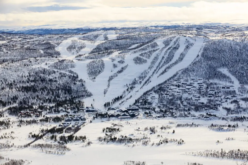 Aerial view of Geilo ski resort with snow-covered slopes and forested areas, showcasing winter sports in Norway for tourism