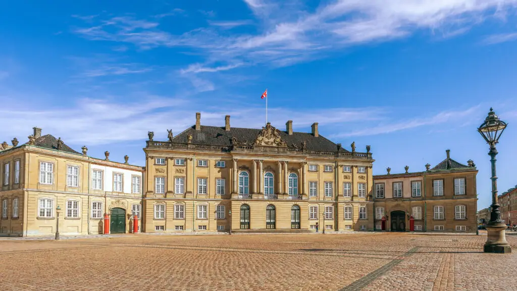 King Christian VIII's Palace at Amalienborg, showcasing elegant architecture and Danish flag under blue sky, Copenhagen, Denmark
