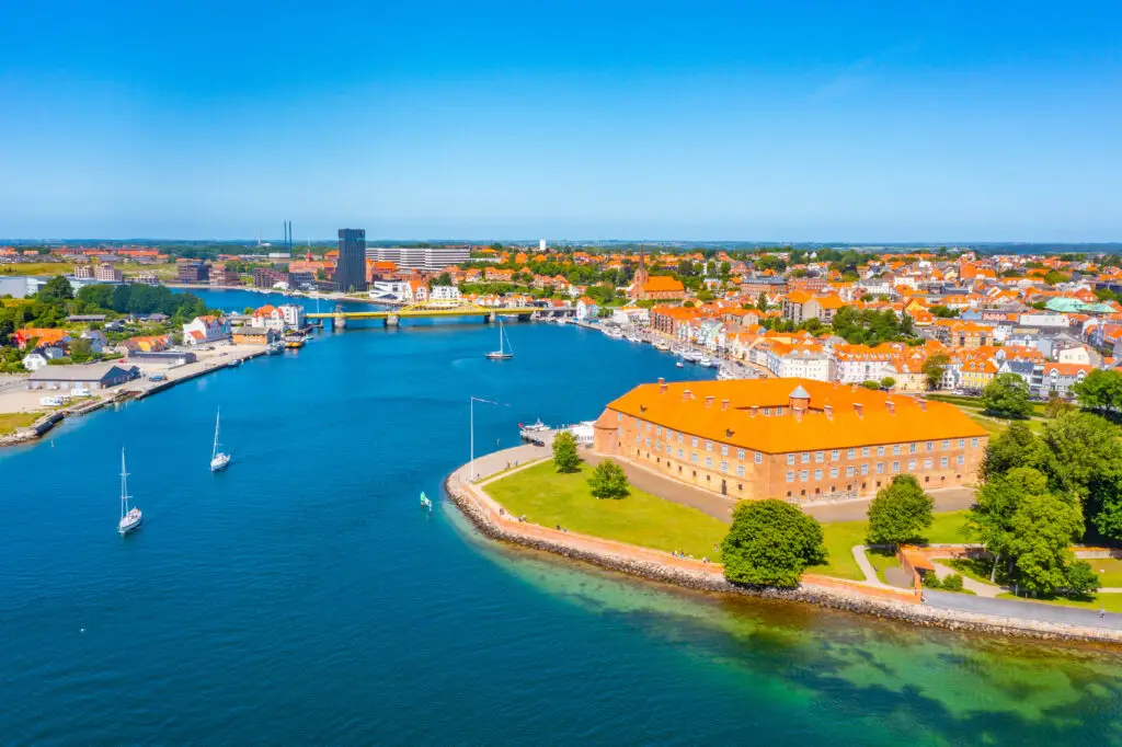 Aerial view of Sonderborg, Denmark showing the scenic waterfront with boats, historic buildings, and lush greenery