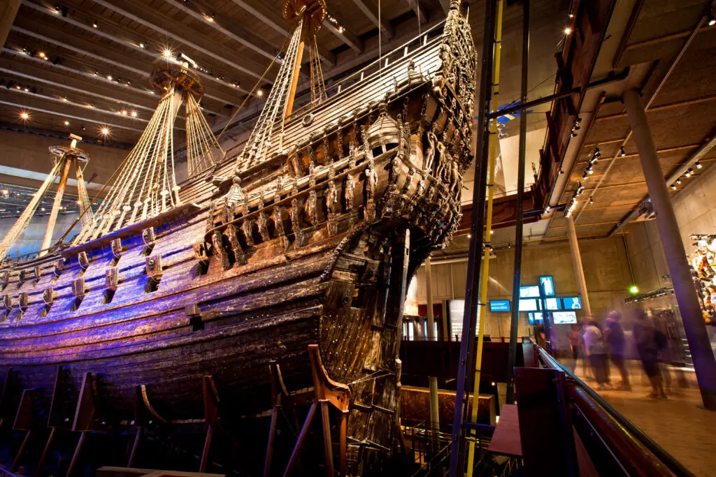 Impressive display of the Vasa ship at the Vasa Museum in Stockholm, Sweden, showcasing the well-preserved maritime vessel with intricate wooden carvings under dramatic lighting.
